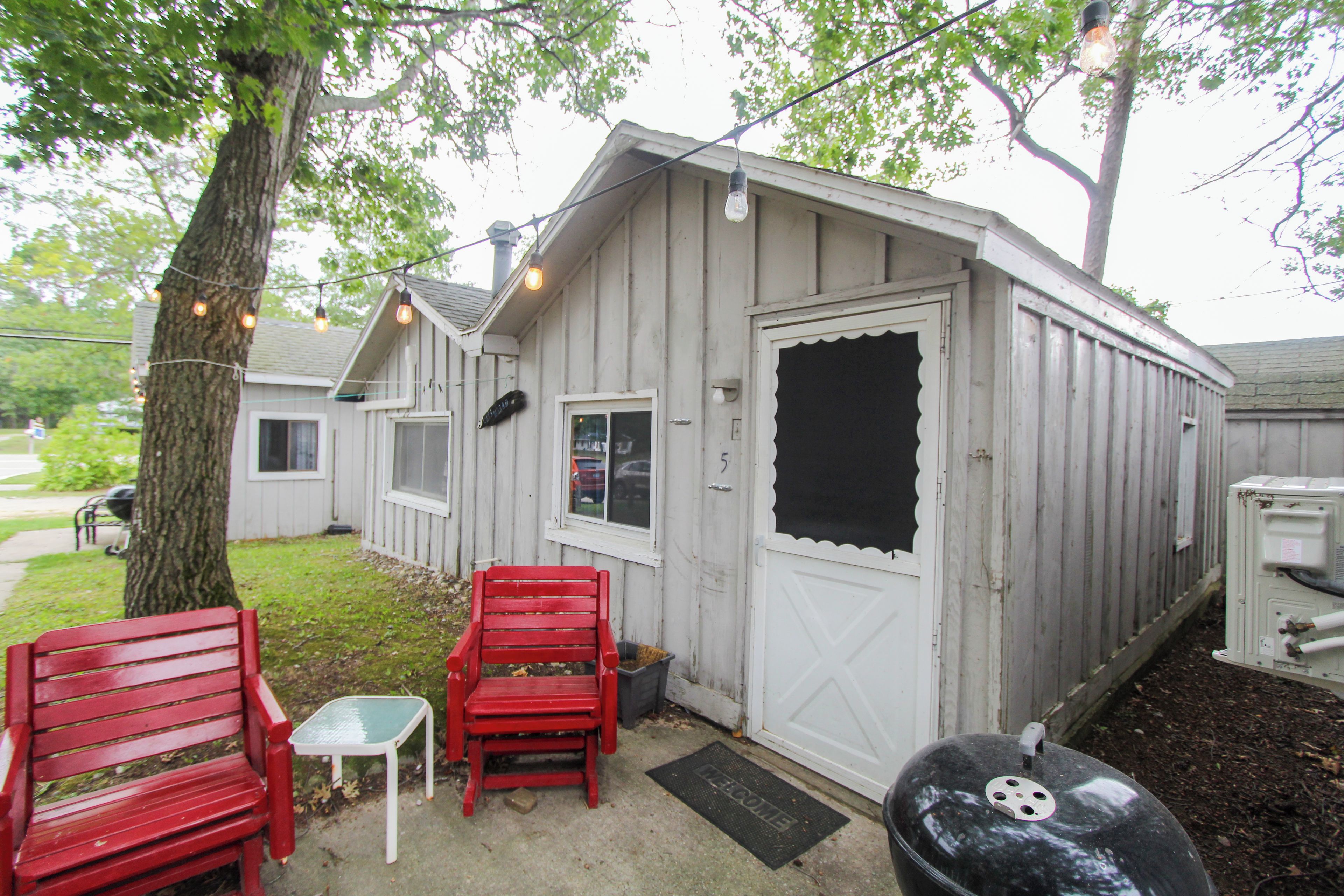 A small, single-story building with a white exterior, a door with a window, and a red bench outside.
