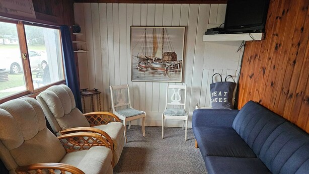 Una habitación acogedora con un sofá azul, dos sillones de mimbre, una mesita y un cuadro enmarcado en la pared.
