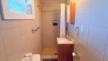 A compact bathroom with a toilet, sink, and shower area.