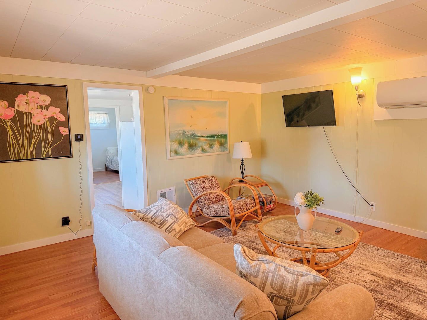 A living room with a sofa, two armchairs, a glass coffee table, and a painting on the wall.