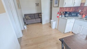 Un espacio habitable compacto con sofá, mesa de comedor y área de cocina que incluye microondas y cafetera.