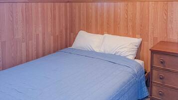 A bedroom with a wooden headboard, a bed with white bedding, a wooden dresser, and three framed pictures on the wall.