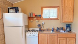 Cocina compacta con refrigerador, estufa y pileta.