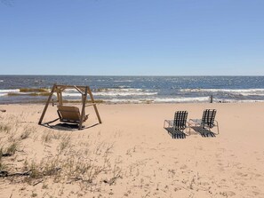 Une plage avec une balançoire et deux chaises donnant sur l’océan.