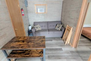 Une petite pièce, de taille modeste, comprenant un canapé, une table en bois, un extincteur et un petit radiateur.