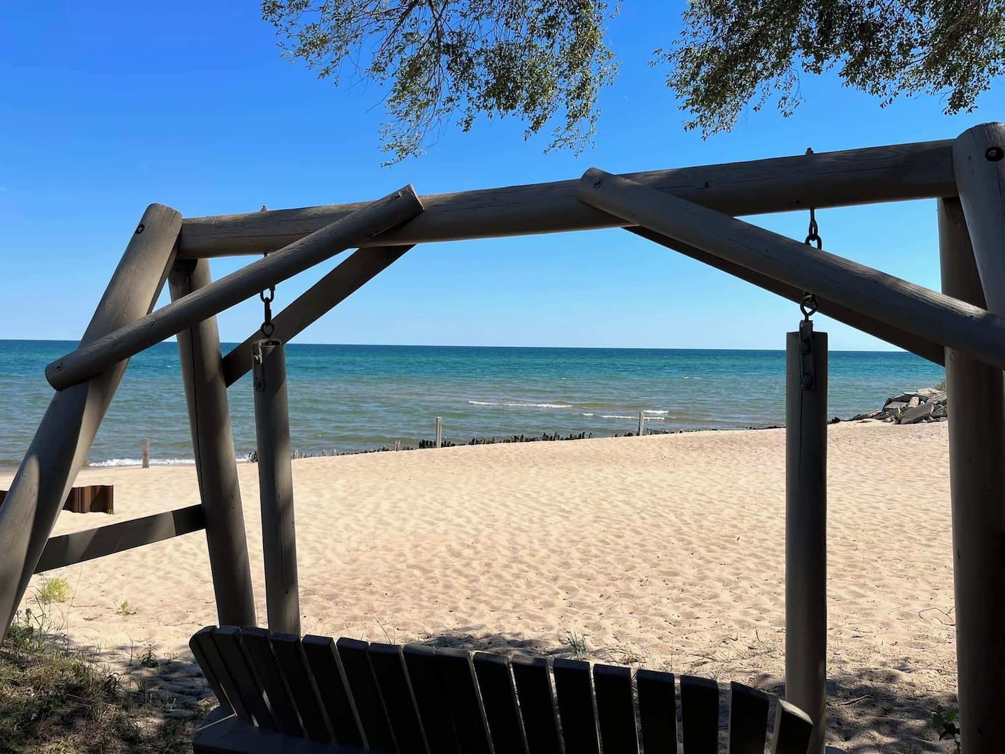 A wooden swing set overlooking a sandy beach with the ocean in the background.