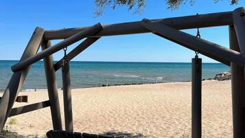 A wooden swing set overlooking a sandy beach with the ocean in the background.