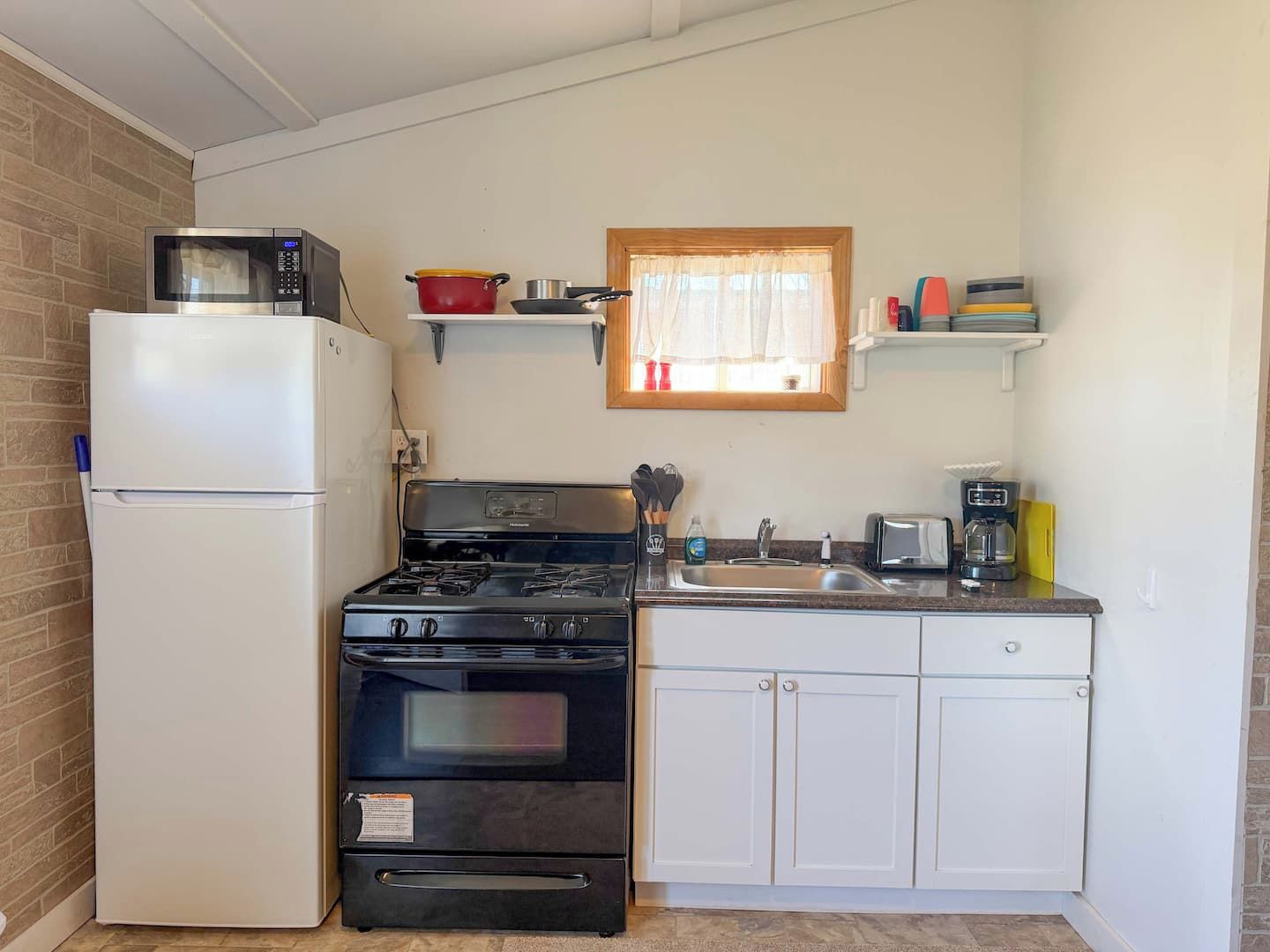 Una cocina compacta equipada con refrigerador, estufa, horno y pileta.