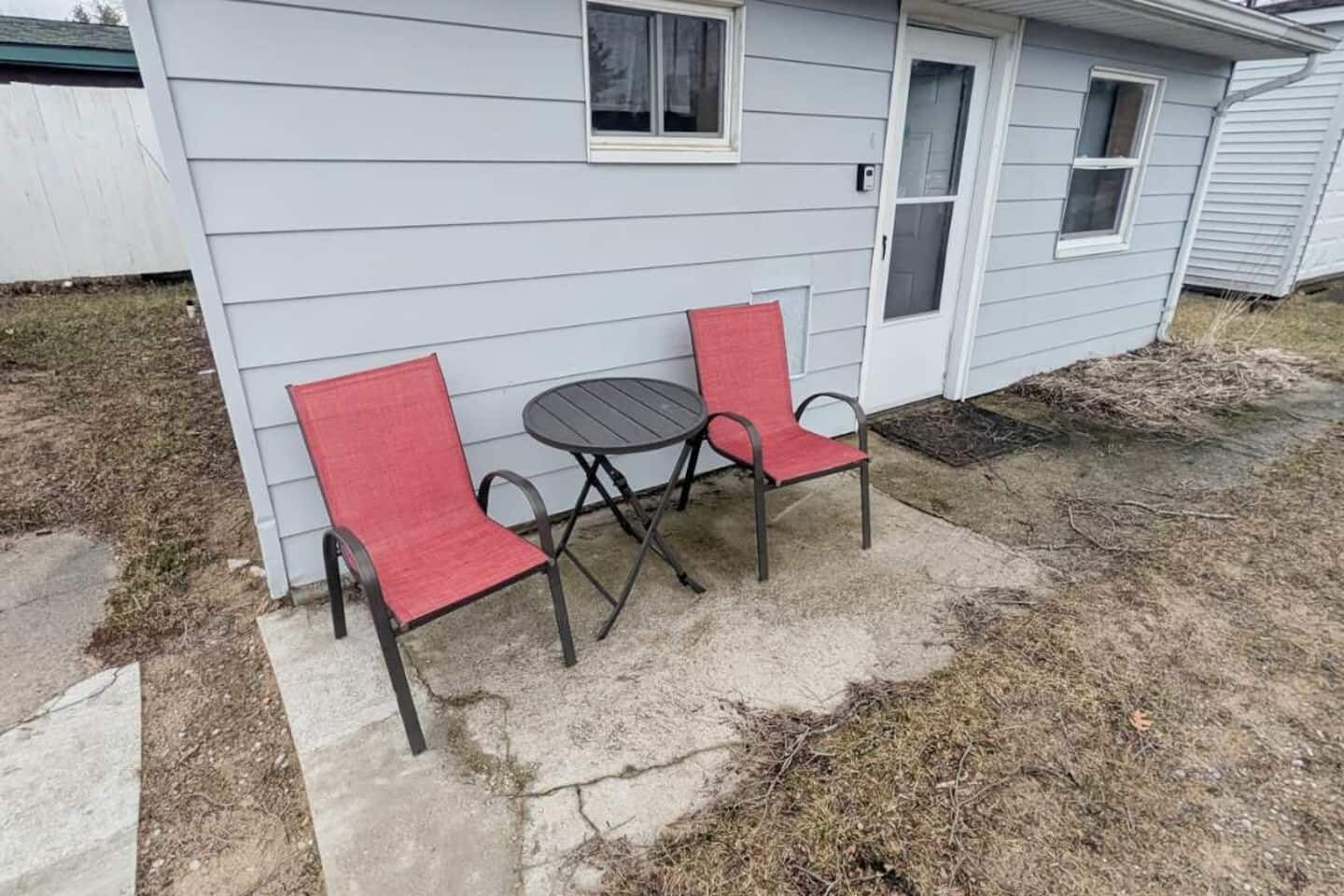 Una casita con un patio que tiene una mesa y dos sillas.