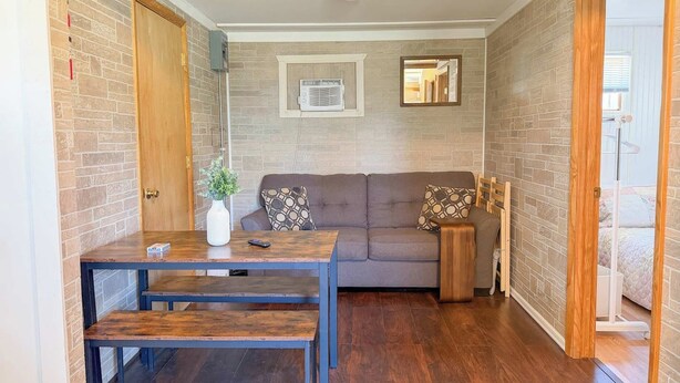 Una habitación con una mesa de madera, un sofá y una mesita auxiliar.