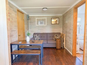 Una habitació amb taula de fusta, un sofà i una taula auxiliar.