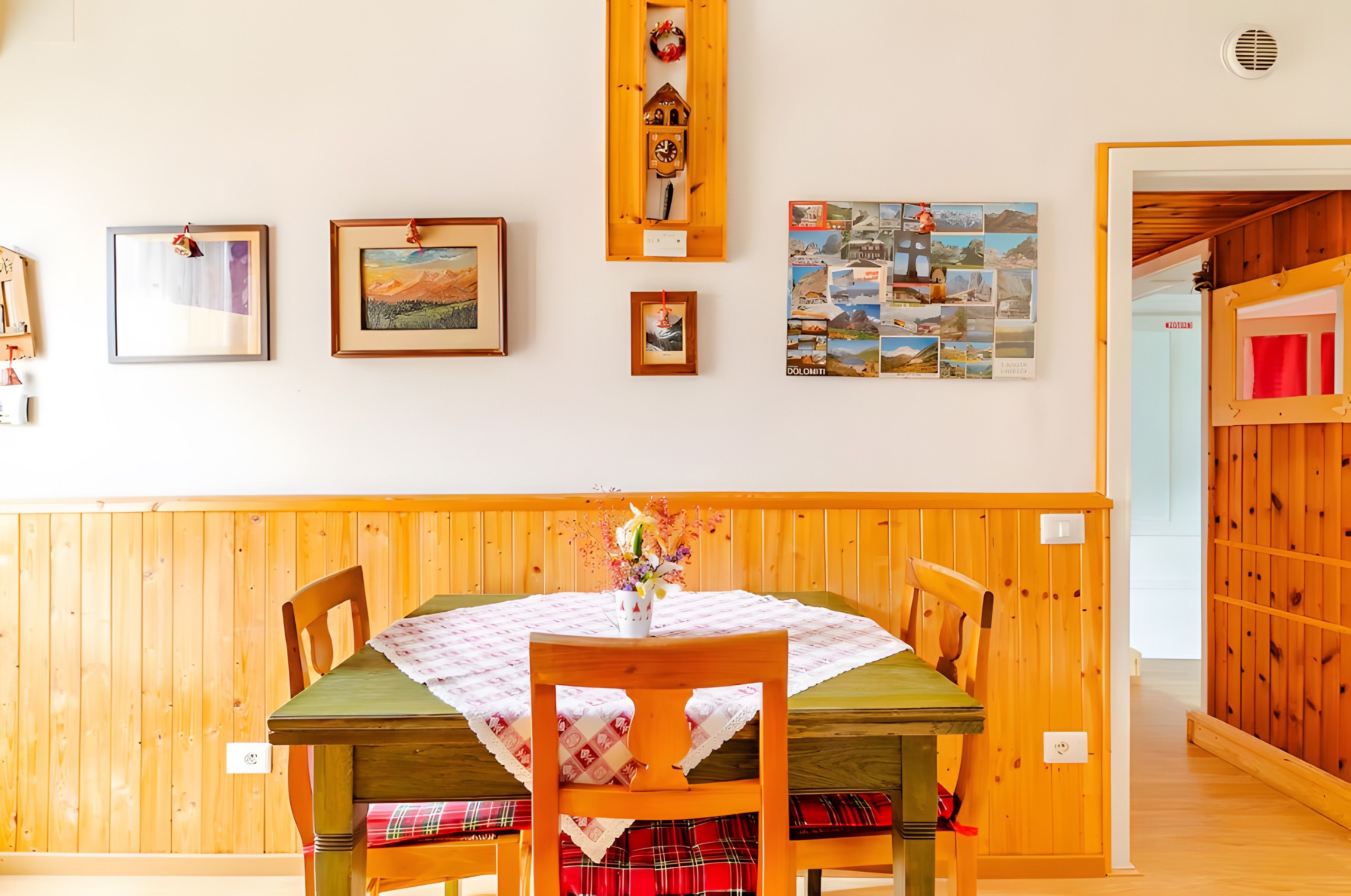 Un coin repas avec une table et des chaises en bois, un mur orné de tableaux encadrés et un mur recouvert de panneaux de bois.