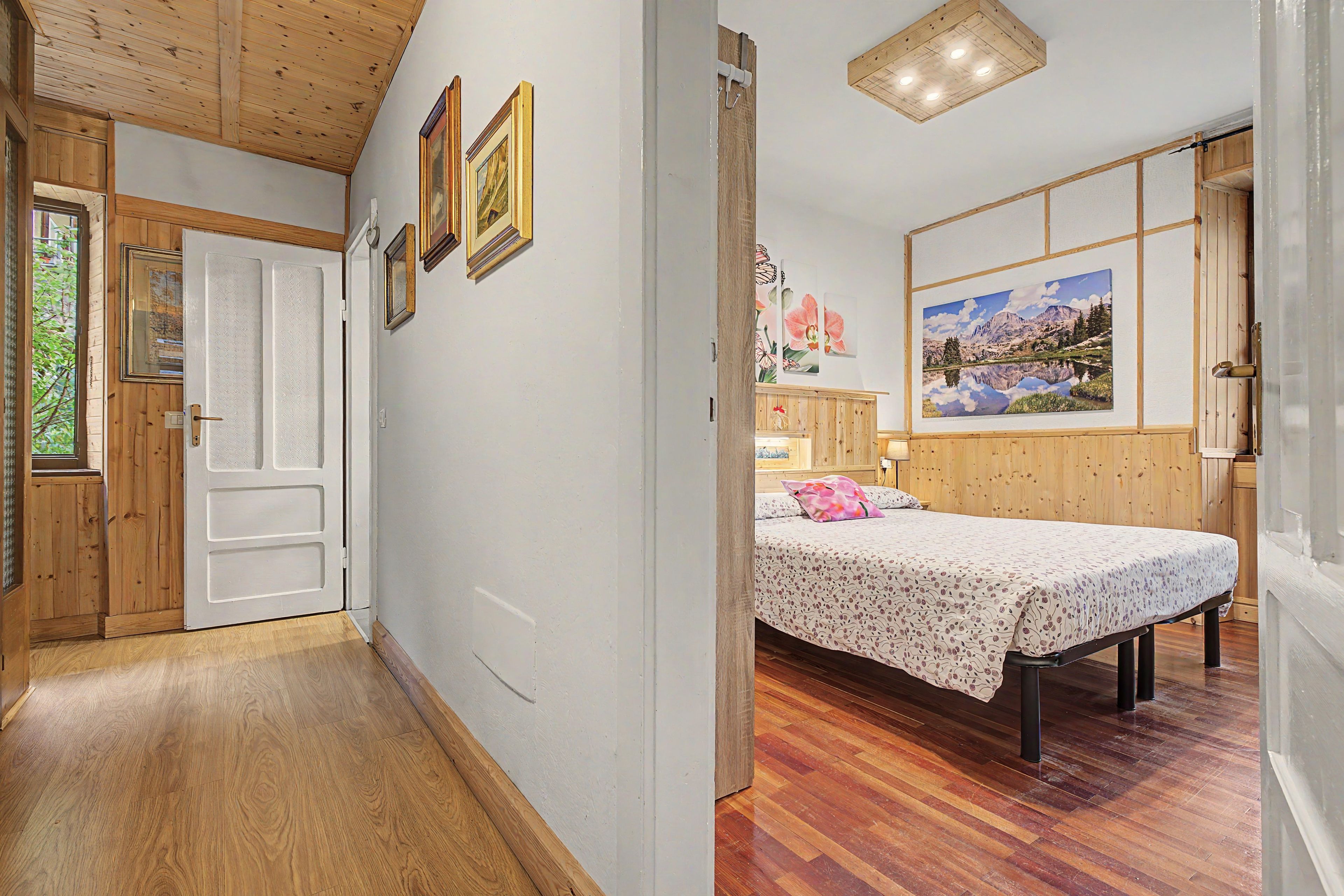 Una habitación con cama, suelo de madera y un cuadro en la pared.