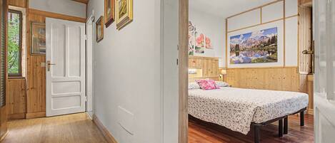 A room with a bed, wooden flooring, and a painting on the wall.