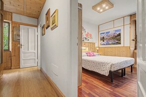 A room with a bed, wooden flooring, and a painting on the wall.
