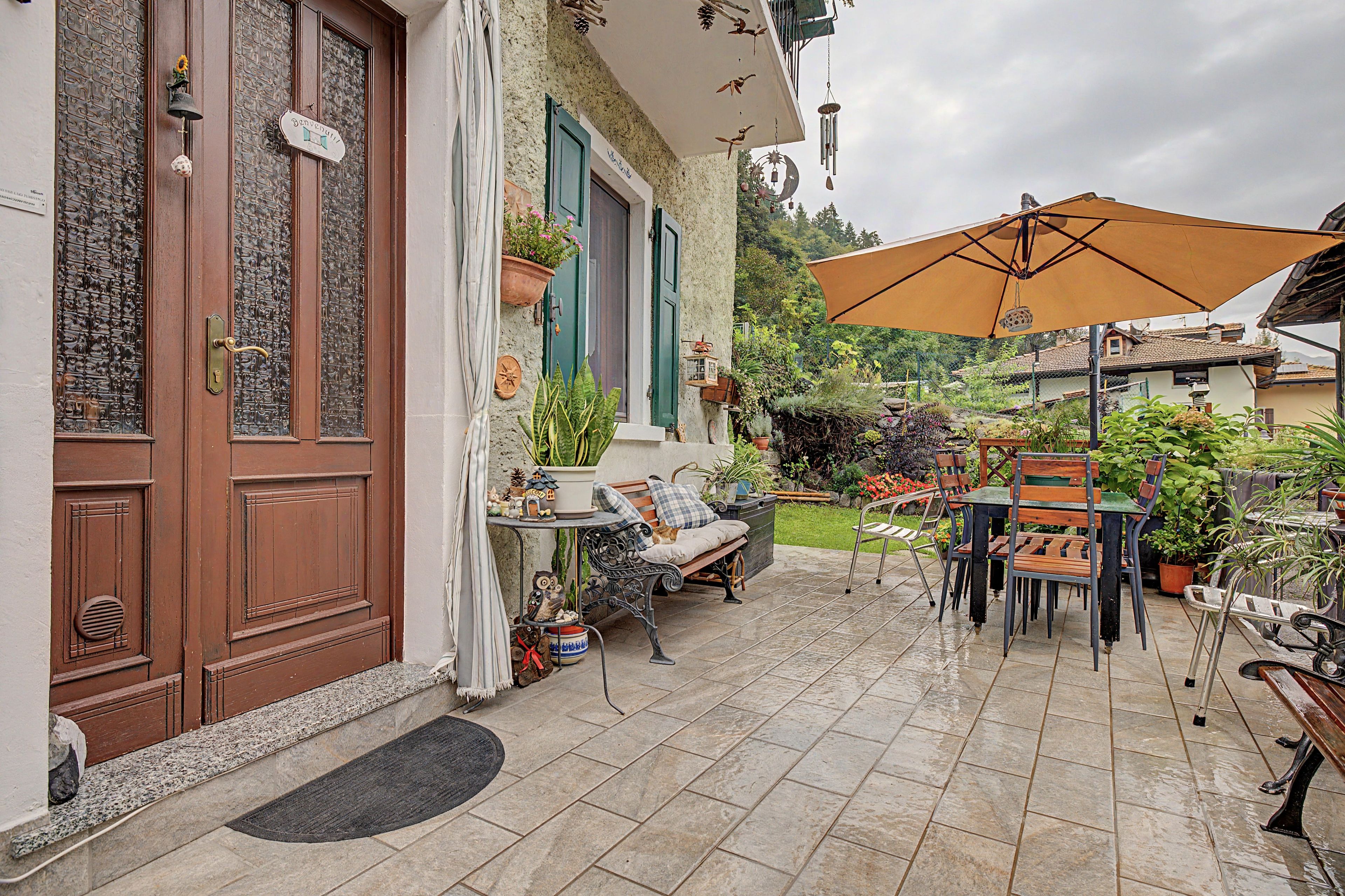 Eine Terrasse mit Esstisch, Stühlen und einem großen Sonnenschirm.