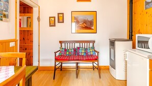 Un espacio habitable funcional con un banco de madera, una pequeña kitchenette y una pared decorada con fotografías enmarcadas.