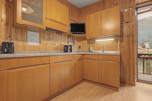 A kitchen with wooden cabinets, a microwave, a coffee maker, and a sink.