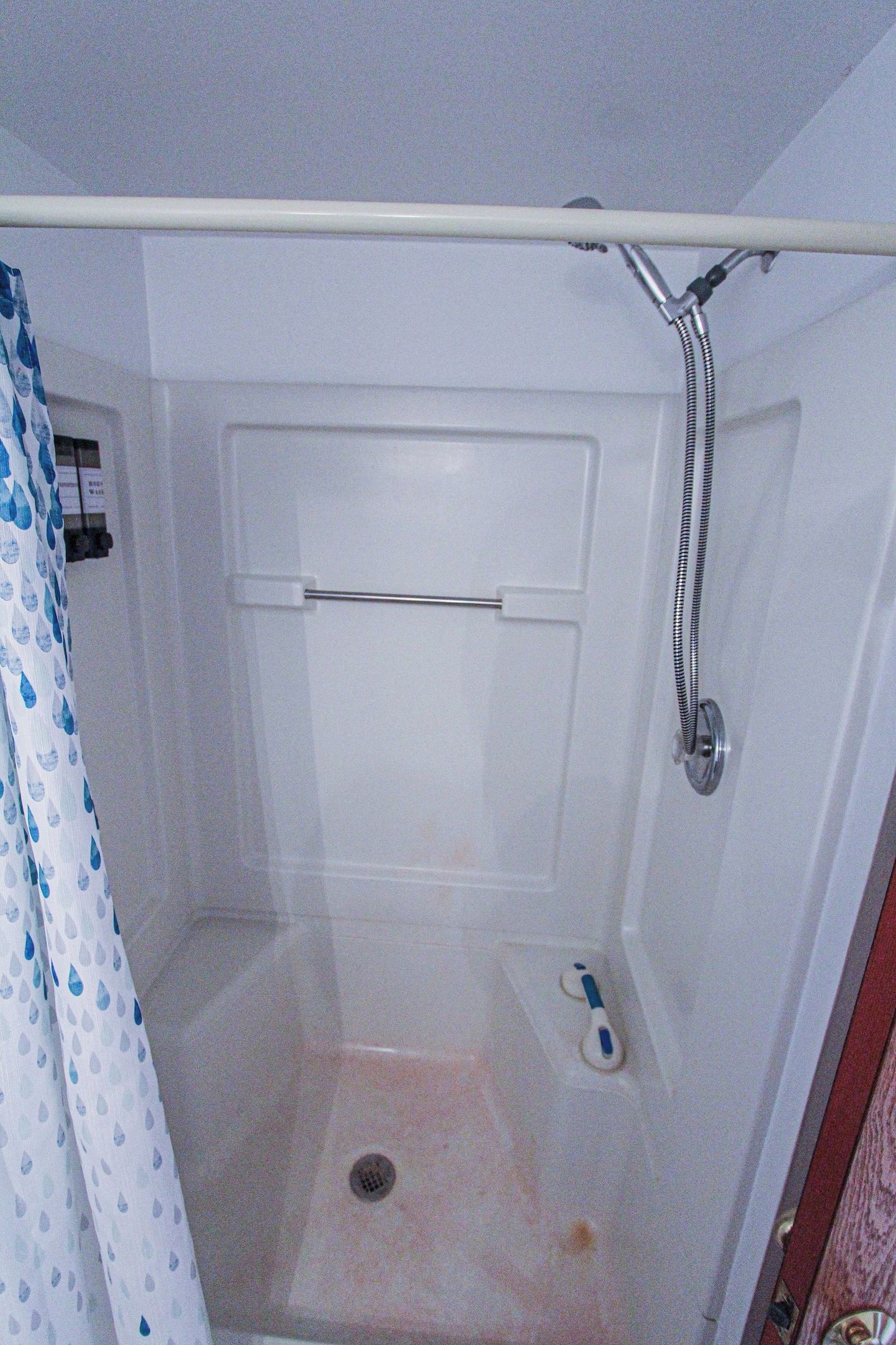 Une cabine de douche équipée d’un pommeau de douche, d’une barre à serviettes et d’un drain.