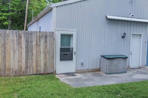 A single-story building with a white door, a small window, and a metal shed with a green roof. - A budget-friendly, freshly renovated studio at Sunnyside, just steps from the lake. (Greenbush)