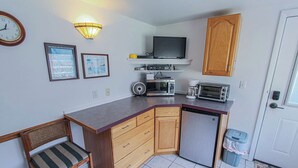 A compact kitchen with a microwave, toaster, and small refrigerator. There is a wooden cabinet, a chair, and a clock on the wall. - A budget-friendly, freshly renovated studio at Sunnyside, just steps from the lake. (Greenbush)