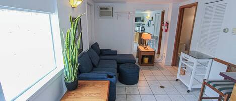 Ein Wohnzimmer mit Ecksofa, Couchtisch aus Holz und einer Topfpflanze.