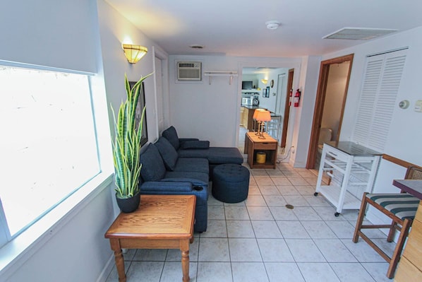 Una sala de estar con un sofá modular, una mesa de centro de madera y una planta en maceta.