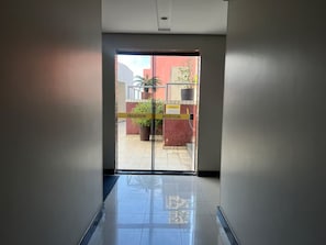 A hallway leading to a glass door with a sign indicating 'Area of the pool.' - 1303 · Noble and Modern with garage 1303 (Belém)