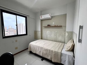 A hotel room with a bed, a window, an air conditioning unit, and a view of city buildings. - 1303 · Noble and Modern with garage 1303 (Belém)