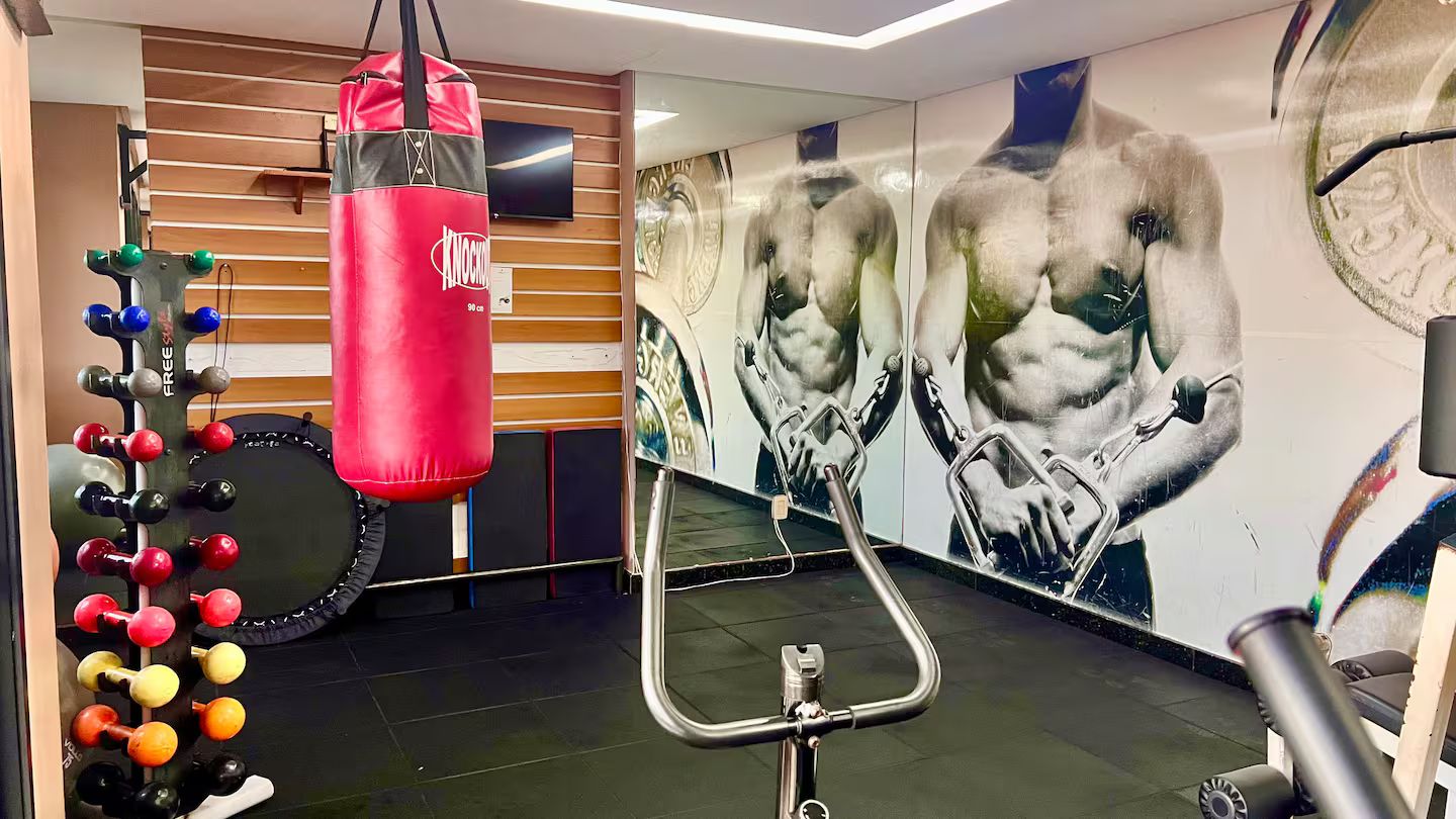 A gym with a punching bag, weight plates, and a wall mural.