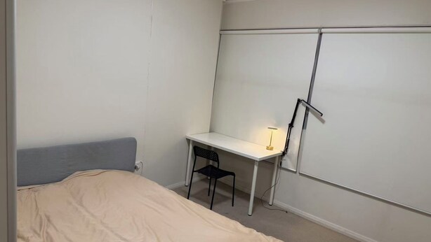 A bedroom with a bed, a desk, a chair, and a wardrobe. - Lunara Hotel (Burwood)