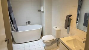 A bathroom with a bathtub, toilet, and sink. - Lunara Hotel (Burwood)