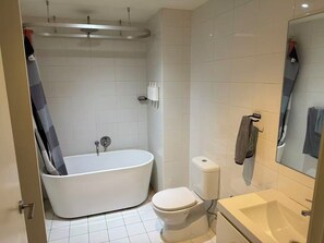 A bathroom with a bathtub, toilet, and sink. - Lunara Hotel (Burwood)