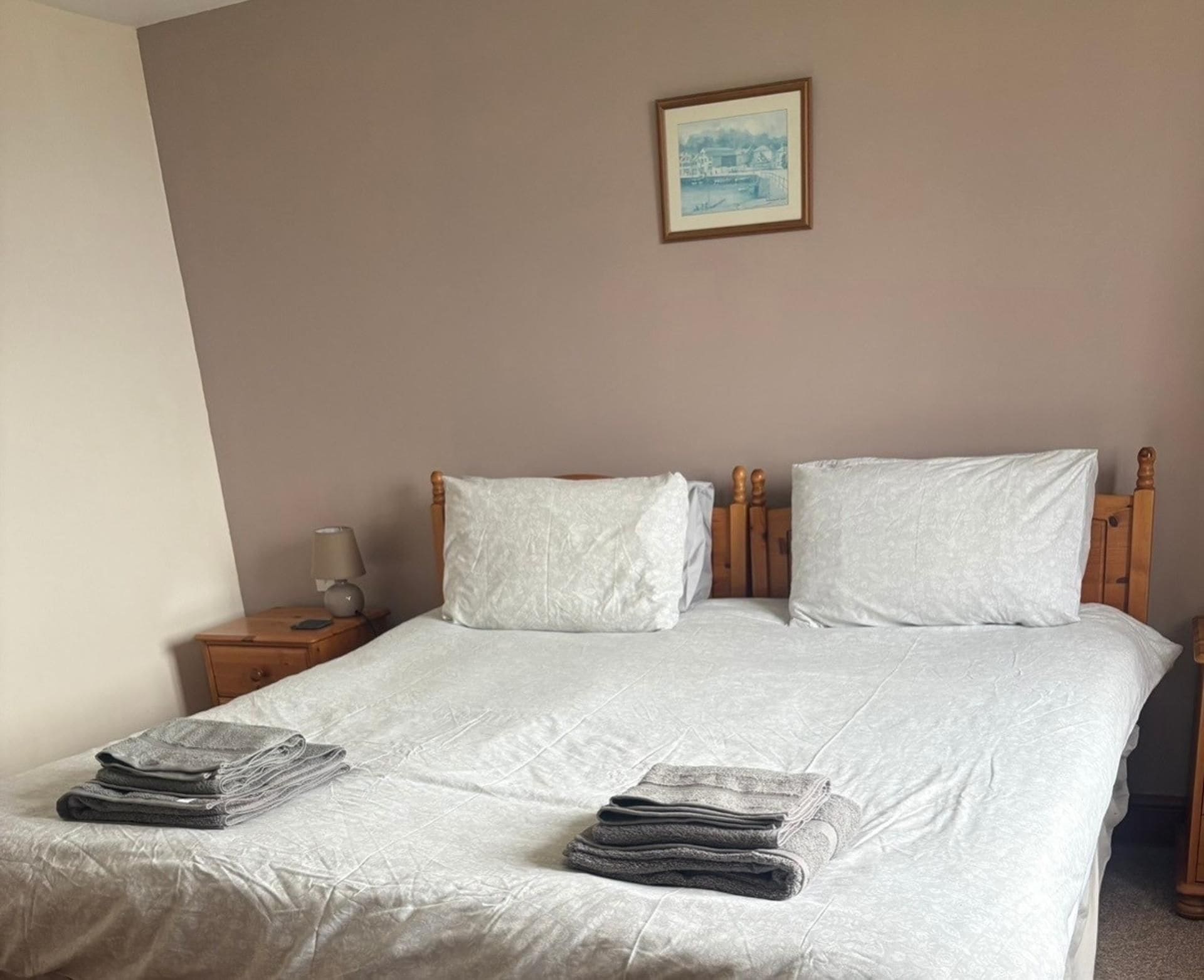 A neatly made bed with white linens, two pillows, and a folded towel on the bed.