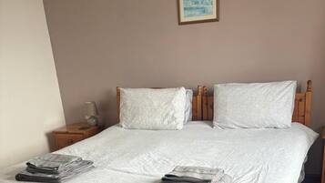 A neatly made bed with white linens, two pillows, and a folded towel on the bed.
