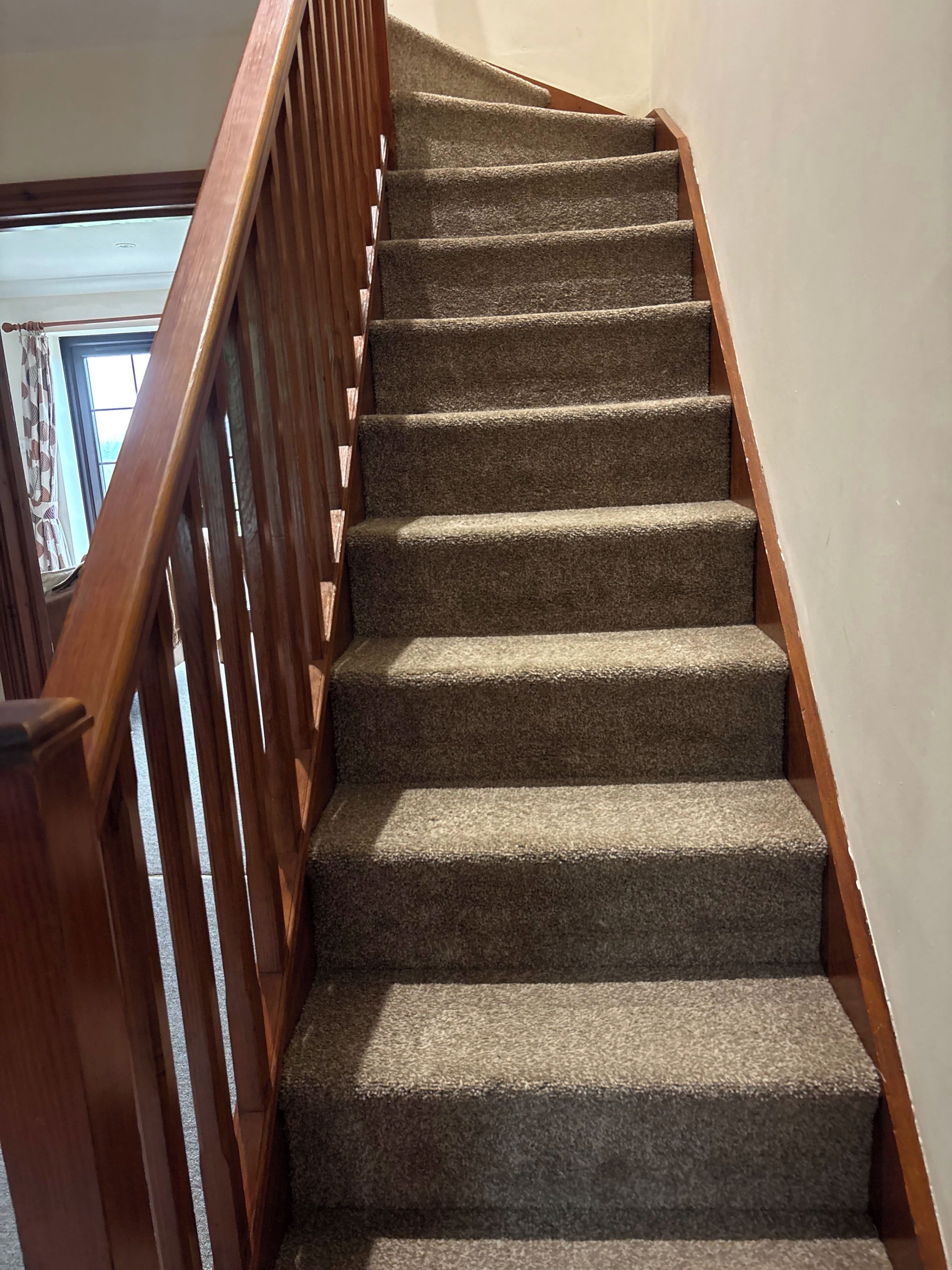 A carpeted staircase with wooden handrails.