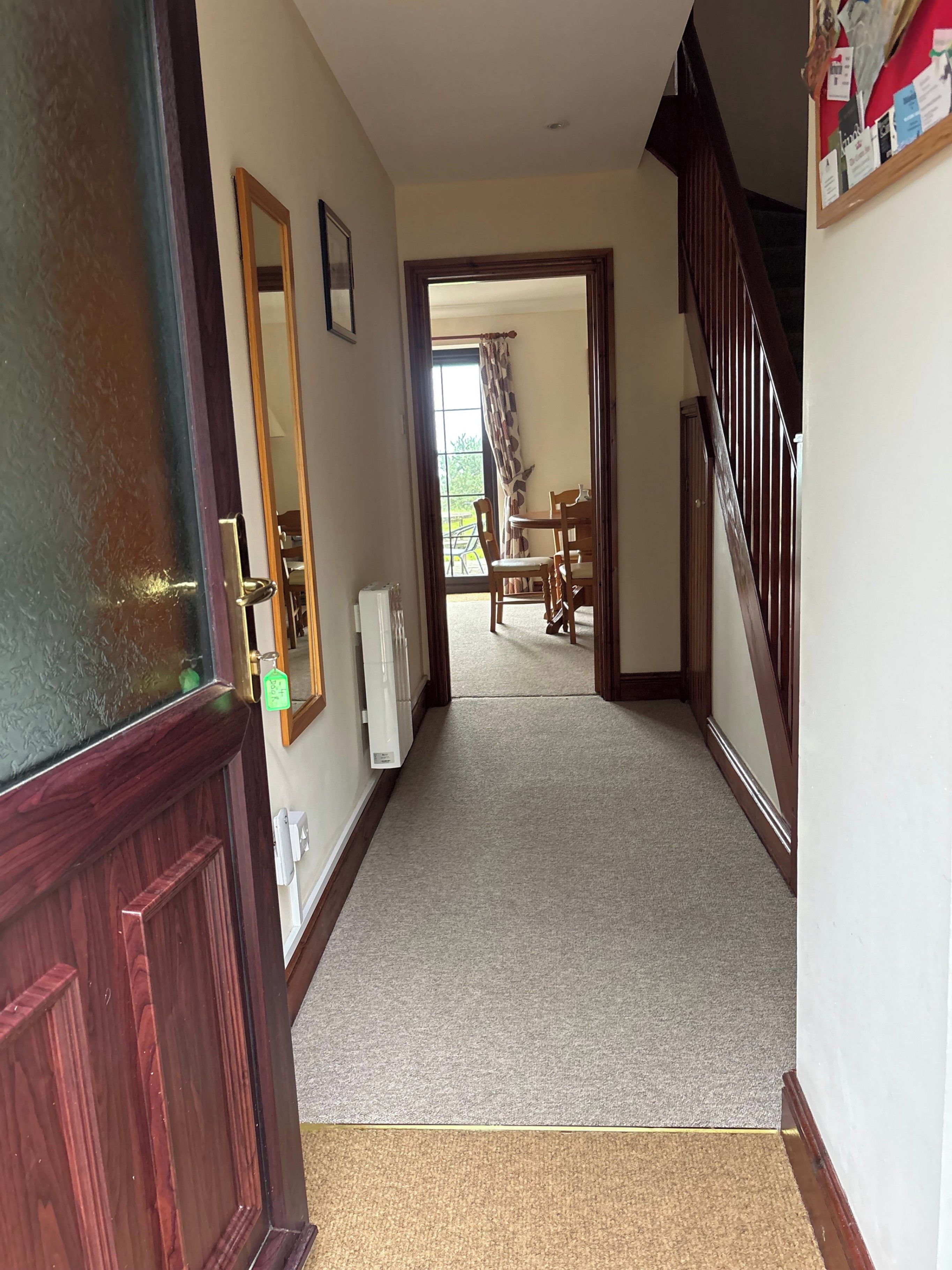 A hallway with a wooden door, a radiator, and a window with curtains.