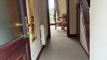 A hallway with a wooden door, a radiator, and a window with curtains.