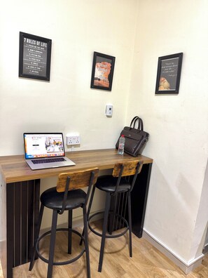 Um espaço de trabalho com laptop, duas cadeiras, uma mesa e cartazes motivacionais na parede.