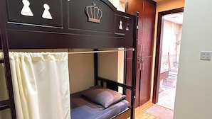 Ein Stockbett mit Kopfstück, einer Vorhang und einer Tür zu einem Badezimmer.