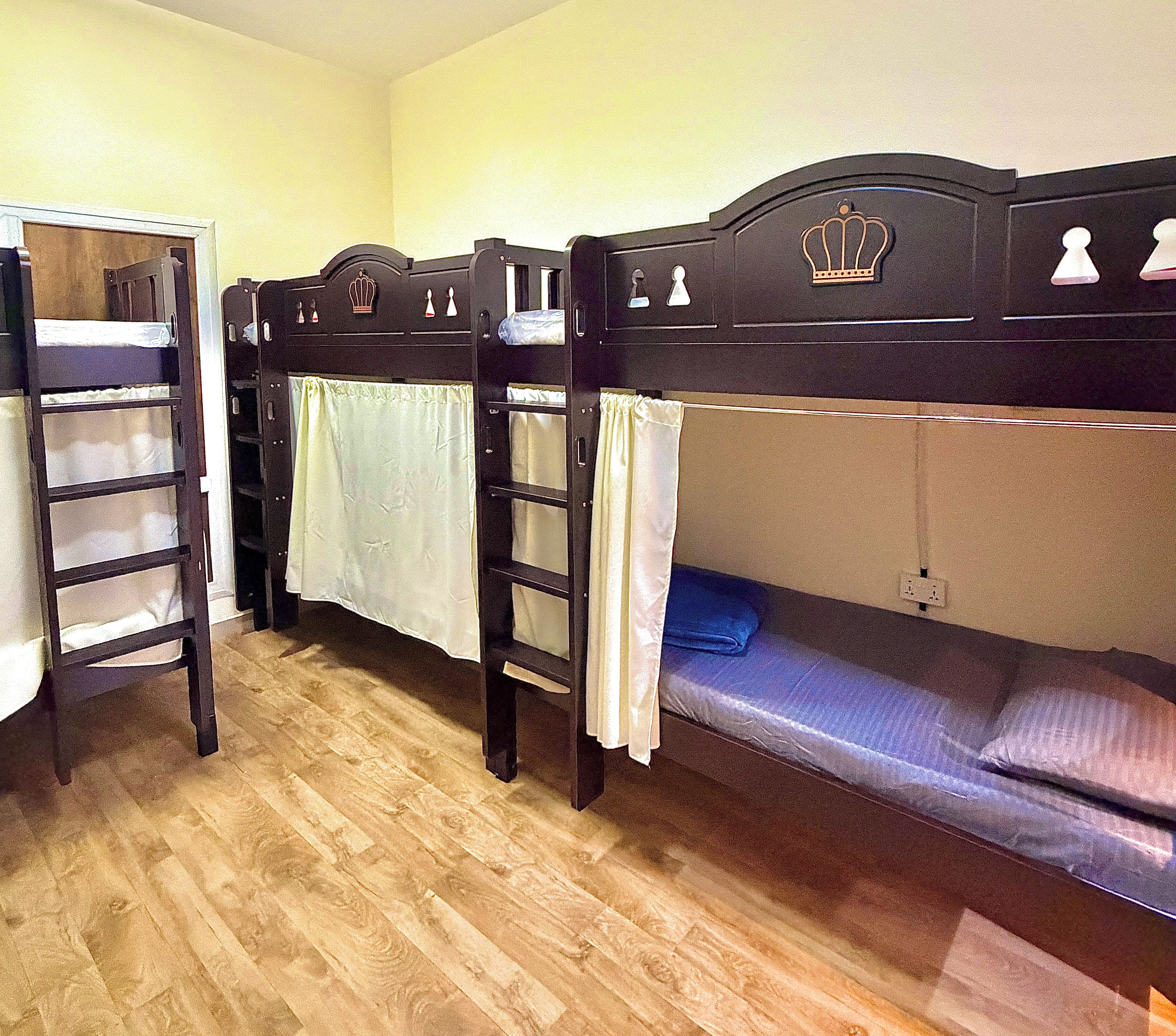 A room with bunk beds, wooden headboards, and a simple layout.