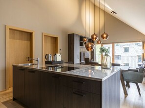A modern kitchen with a large island, dark wood cabinets, and pendant lighting. - Apartment in Schruns With Swimming Pool (Schruns)