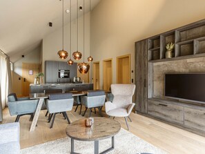 A modern living room with a large TV, grey sofas, a wooden coffee table, and a kitchen in the background. - Apartment in Schruns With Swimming Pool (Schruns)