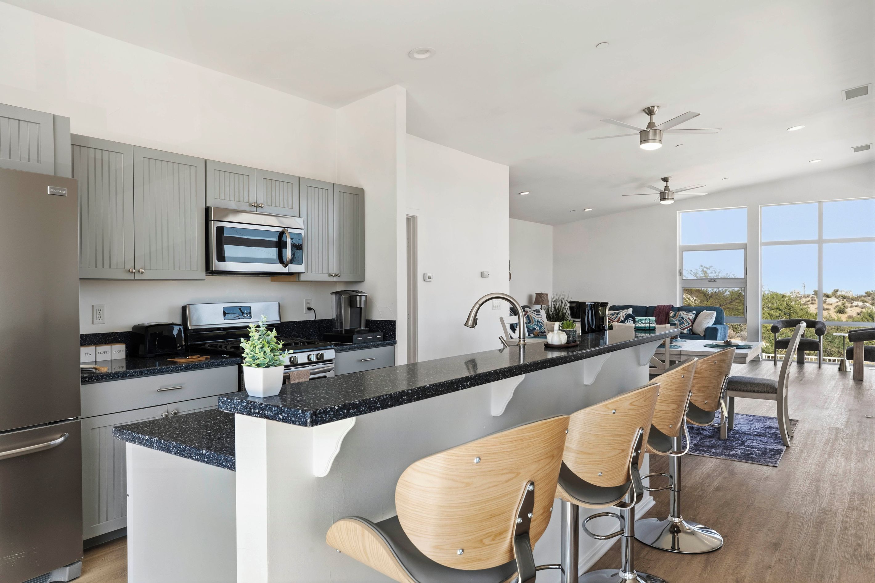 A modern kitchen with a central island, bar stools, and a view of the outdoors.