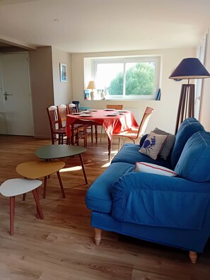 Sala de estar com sofá azul, mesa de jantar de madeira e cadeiras.