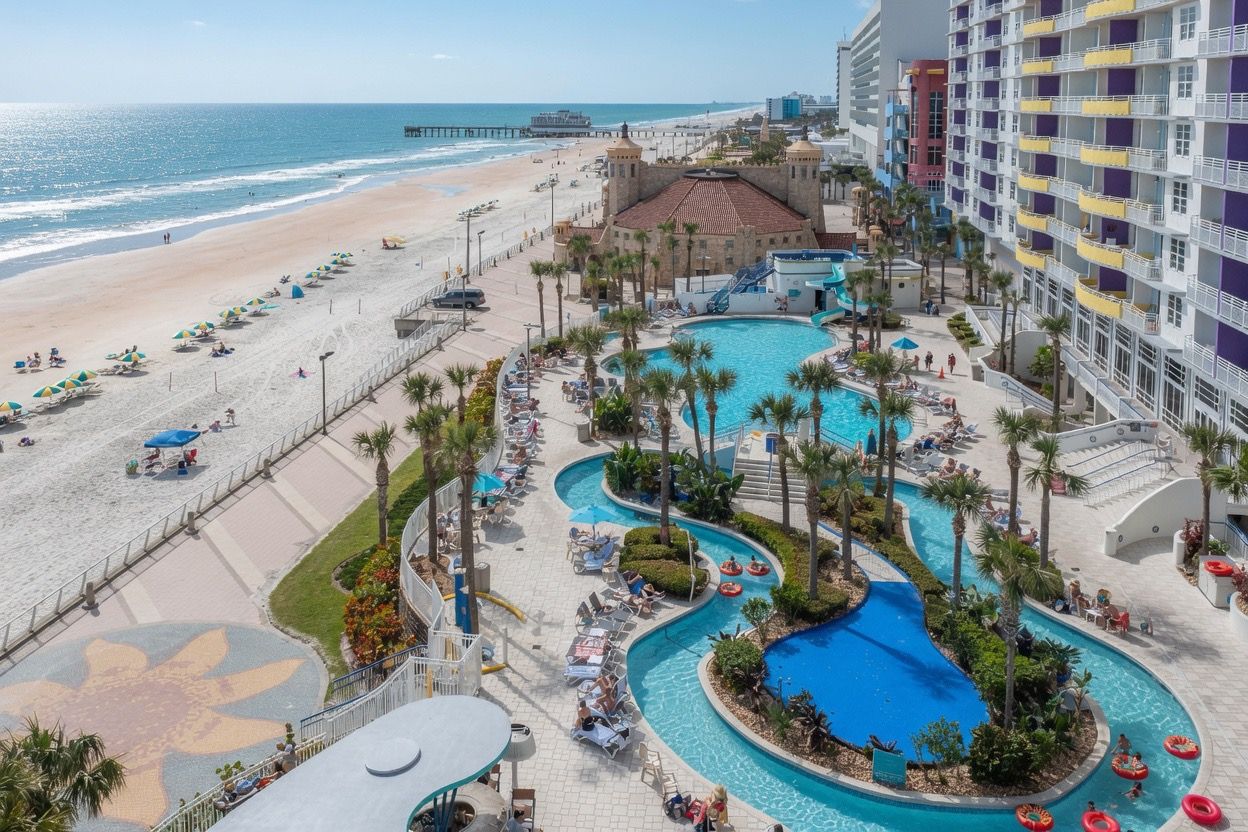 A resort with a beachfront, a pool area with slides, and a large building with balconies.
