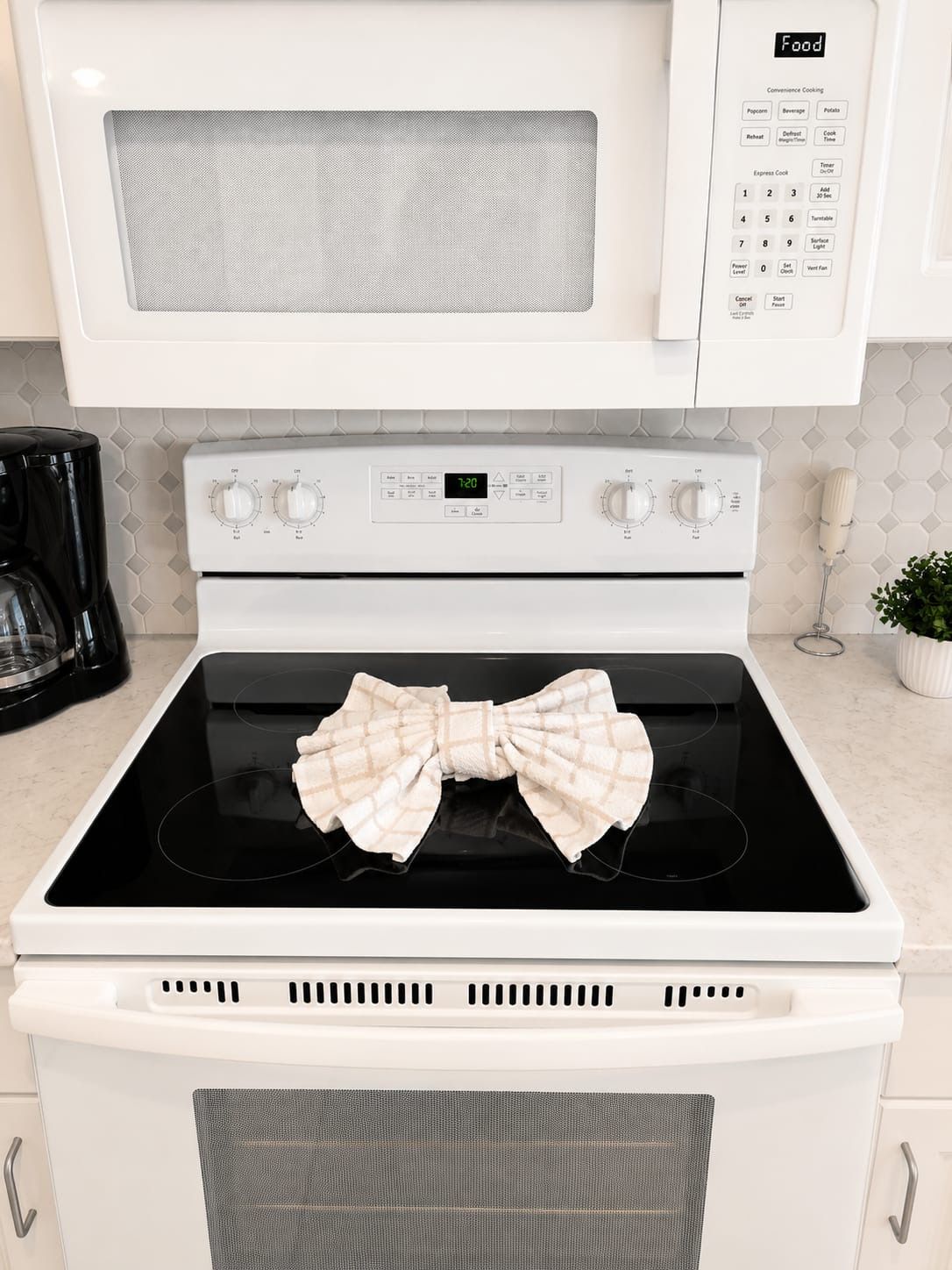 A kitchen with a microwave, oven, and a digital clock displaying 7:20.