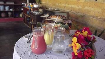 Una mesa con bebidas y un arreglo floral, frente a un muro de ladrillo.