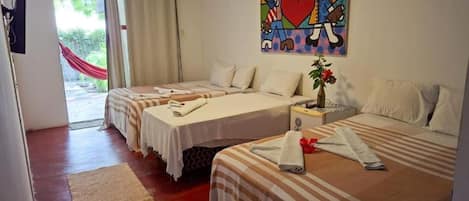 A hotel room with two beds, a painting, a window with curtains, and a red hammock outside.