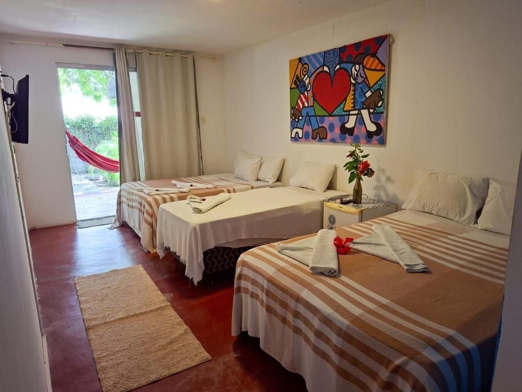 Habitación de hotel con dos camas, un cuadro, una ventana con cortinas y una hamaca roja en el exterior.
